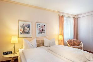 Een hotelkamer met een bed, twee schilderijen aan de muur, een stoel, een lamp en een radio.