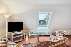 Ein Zimmer mit Fernseher, einem kleinen Tisch, einem Stuhl, einer Heizung und einem Fenster mit Blick.