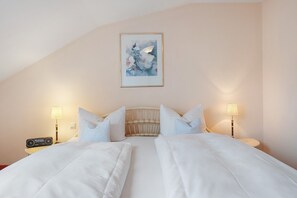 Ein Hotelzimmer mit einem Bett, zwei Nachttischlampen, einem Radio und einem gerahmten Kunstwerk an der Wand.