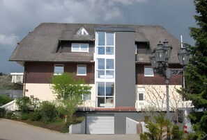 Een woongebouw met twee verdiepingen, een centrale ingang, een garage en een balkon.