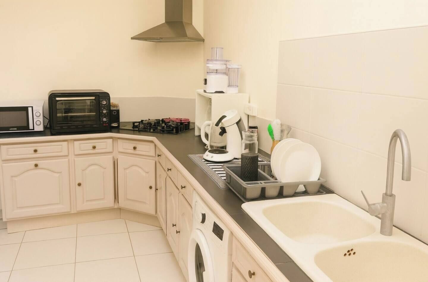 A compact kitchen with a microwave, toaster, coffee maker, and a sink with a faucet.