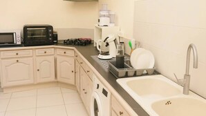 Una cuina compacta amb microones, torradora, cafetera i un rentapeus amb aixeta.
