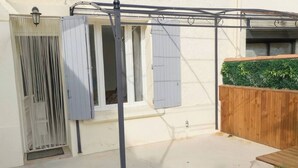 Zona exterior coberta amb estructura metàl·lica, tanca de fusta i finestra amb persianes.