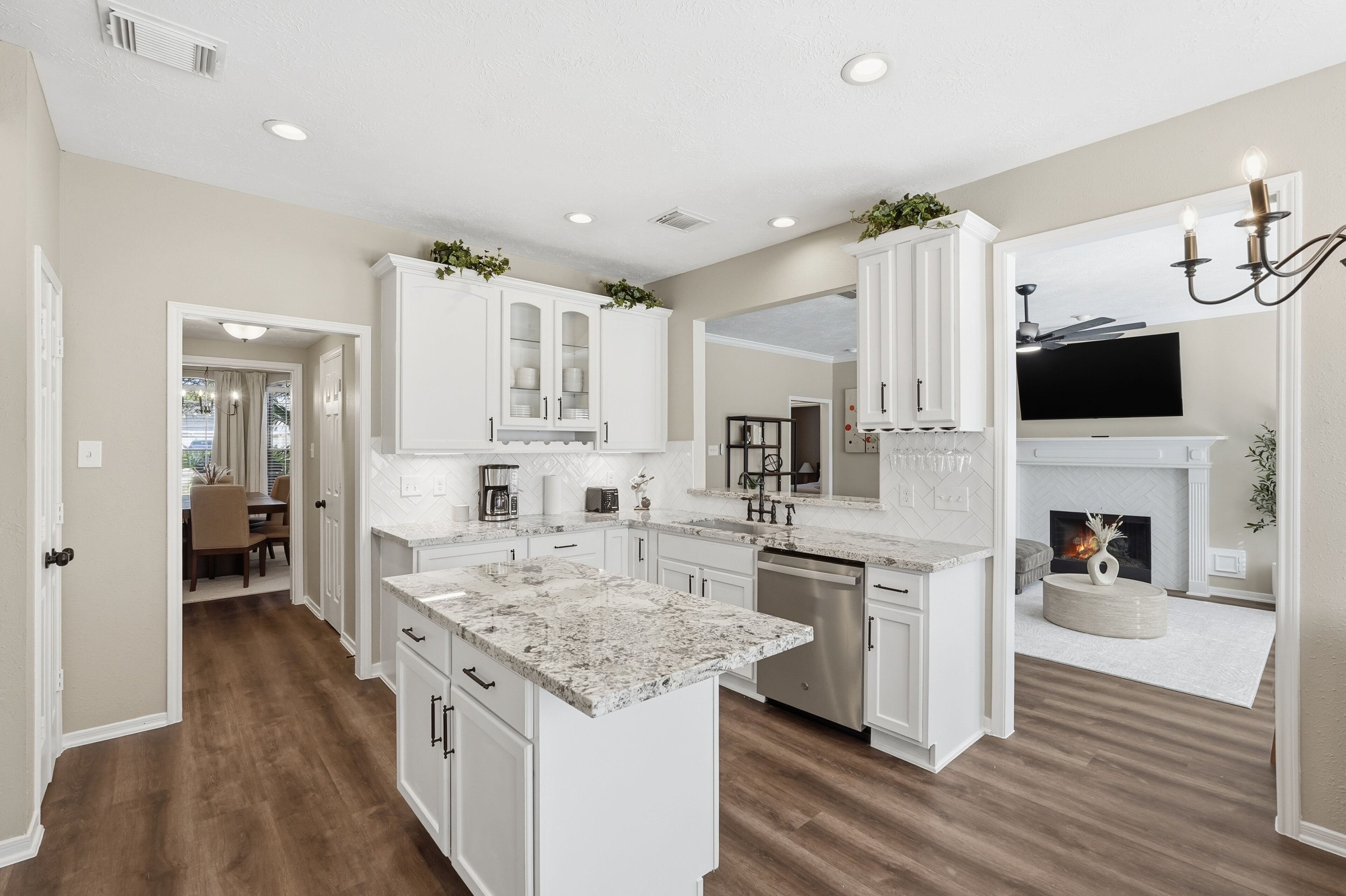 A spacious kitchen with white cabinetry, a central island, and a fireplace.