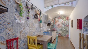 A narrow kitchen with patterned tiles, a wooden table, and chairs. - GuestHost - Charming 74 sqm apartment, ideal for groups or families of up to 4 guests, located on the first floor of a building (a few steps to access / NO elevator).The accommodation is located in a very central area, just a few minutes’ walk from the (Taranto)