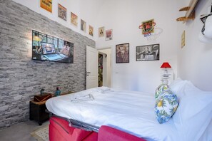 Un dormitorio con una cama, un televisor montado en la pared, un revestimiento de madera y varias fotografías enmarcadas.