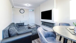 A modern living room with a sofa, a coffee table, a fireplace, and a dining area with chairs.