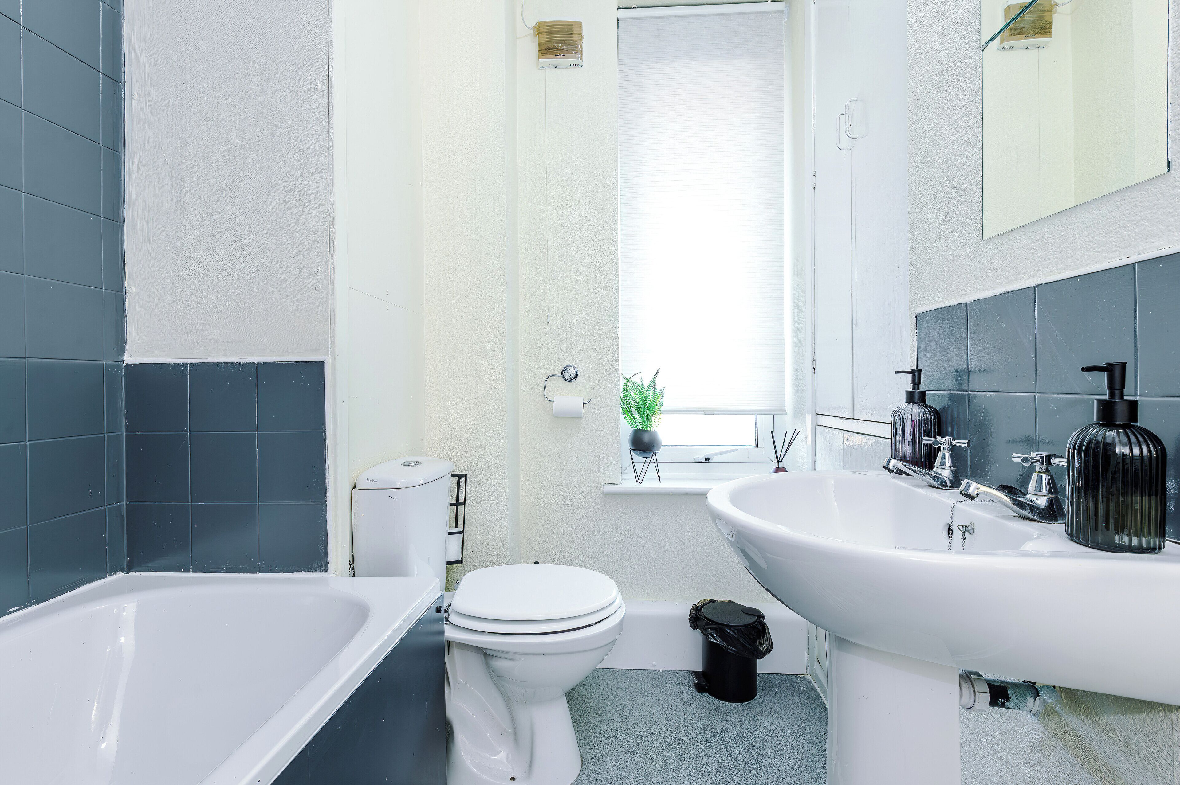 A modern bathroom with a bathtub, toilet, and two sinks.