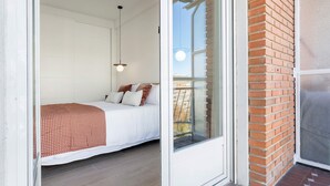 Una camera da letto con un letto, una finestra e una porta che dà su un balcone.