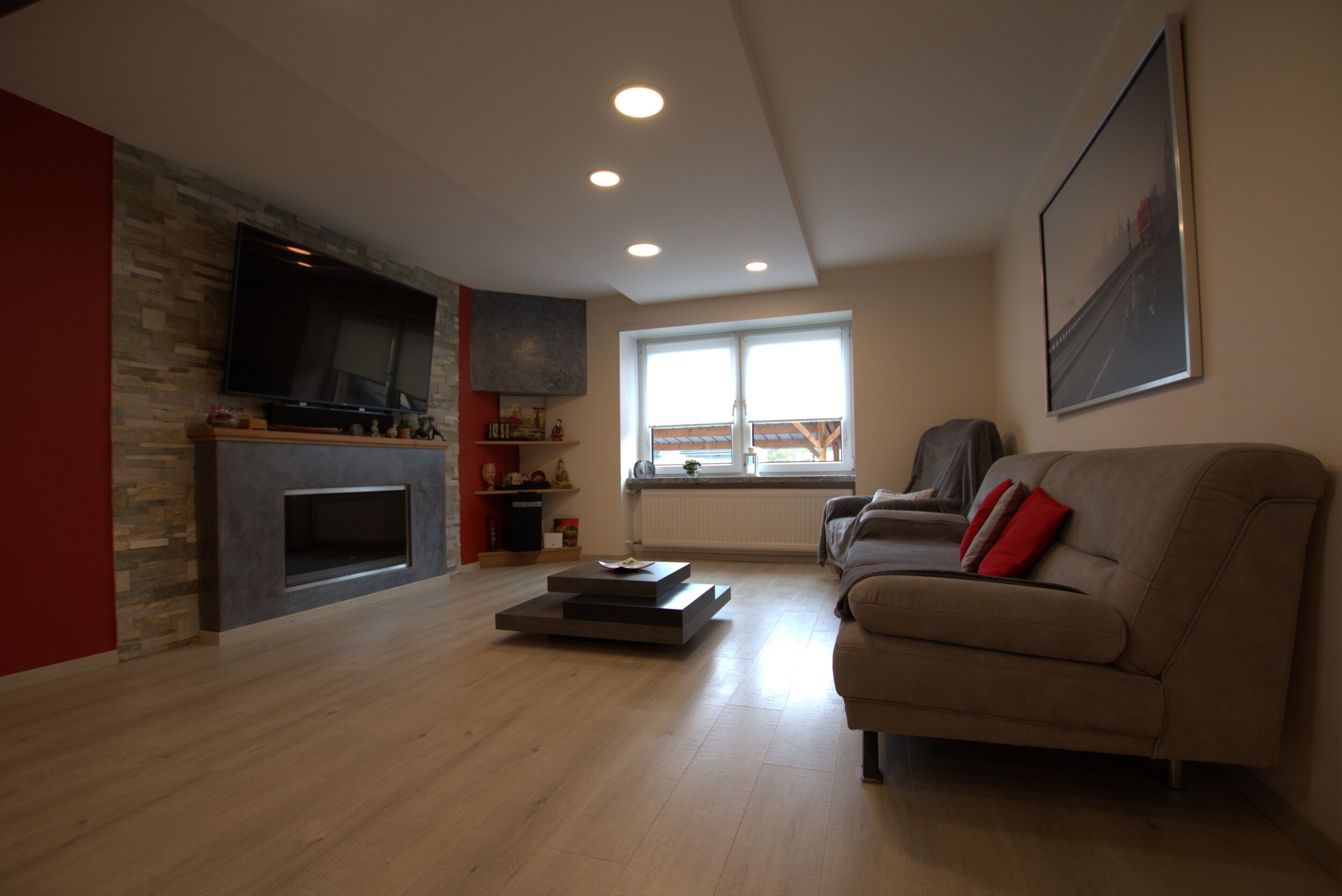 Ein Wohnzimmer mit Kamin, einer Couch, einem Couchtisch und einem an der Wand befestigten Fernseher.