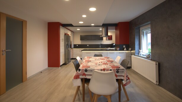 Een moderne keuken met een centraal eiland, witte kasten en een rode accentmuur.