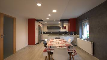 A modern kitchen with a central island, white cabinets, and a red accent wall.