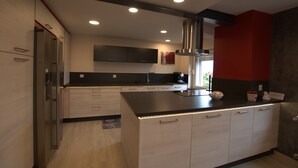 A modern kitchen with a black countertop, stainless steel appliances, and recessed lighting. - Au Jardin Du Levant" gîte with large swimming pool and games room (Holving)