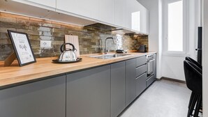 Une cuisine moderne avec un dosseret en pierre, des appareils en acier inoxydable et un plan de travail en bois.