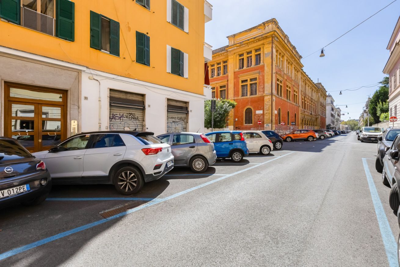 A street lined with parked cars and buildings with shuttered windows.