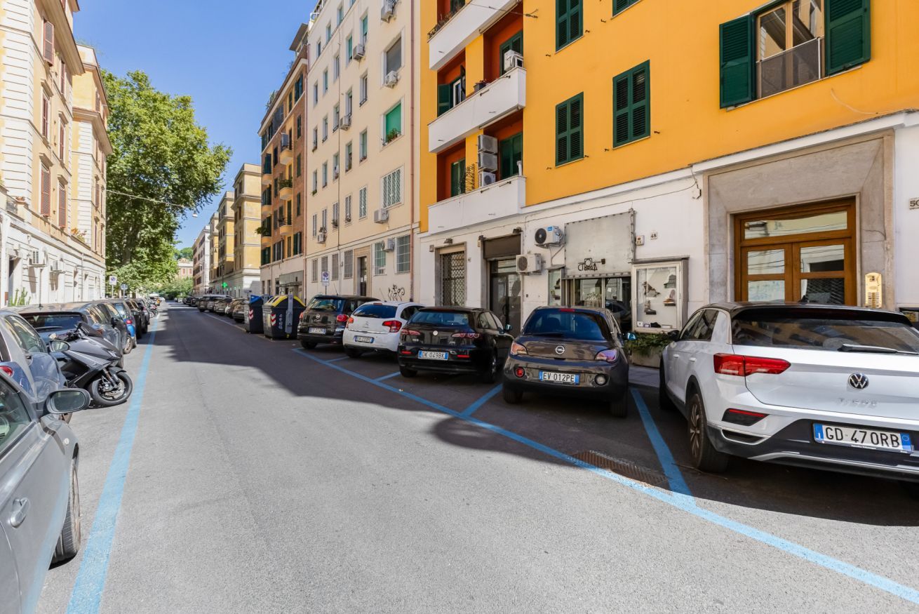 Una calle bordeada por vehículos estacionados y edificios con balcones.