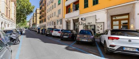 Una calle bordeada por vehículos estacionados y edificios con balcones.