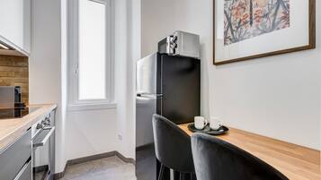 A compact kitchen with a refrigerator, oven, and a dining area with two chairs and a table.