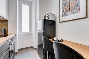 A compact kitchen with a refrigerator, oven, and a dining area with two chairs and a table.