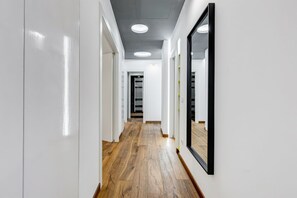 Ein moderner Flur mit Holzboden, weißen Wänden und eingelassenen Deckenleuchten.