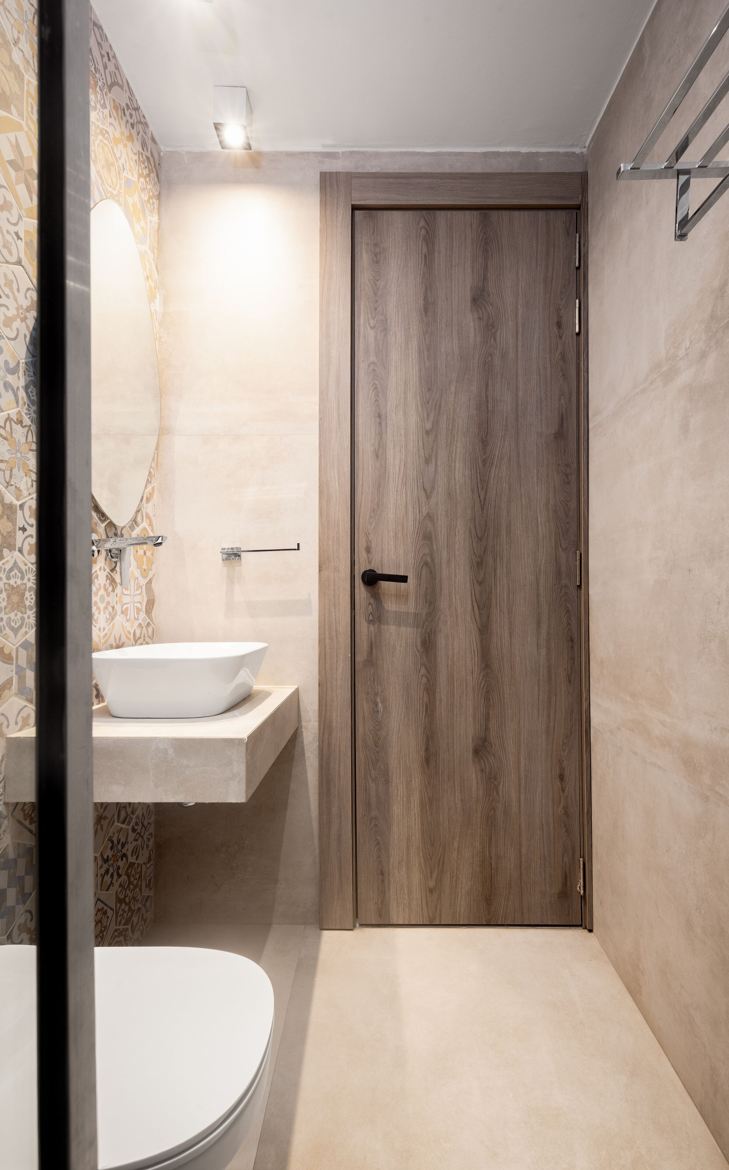 Un bagno moderno con una porta in legno, un lavandino bianco e un water.