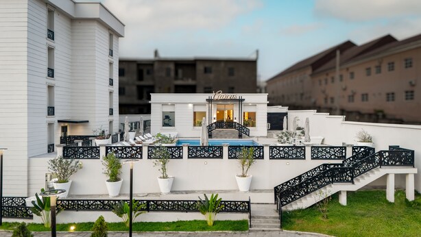 A hotel with a pool, outdoor seating, and a staircase leading to the entrance. - Atlanticblu Hotels & Resorts (Abuja)