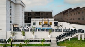 Un hôtel doté d’une piscine, d’un espace extérieur aménagé et d’un escalier menant à l’entrée.