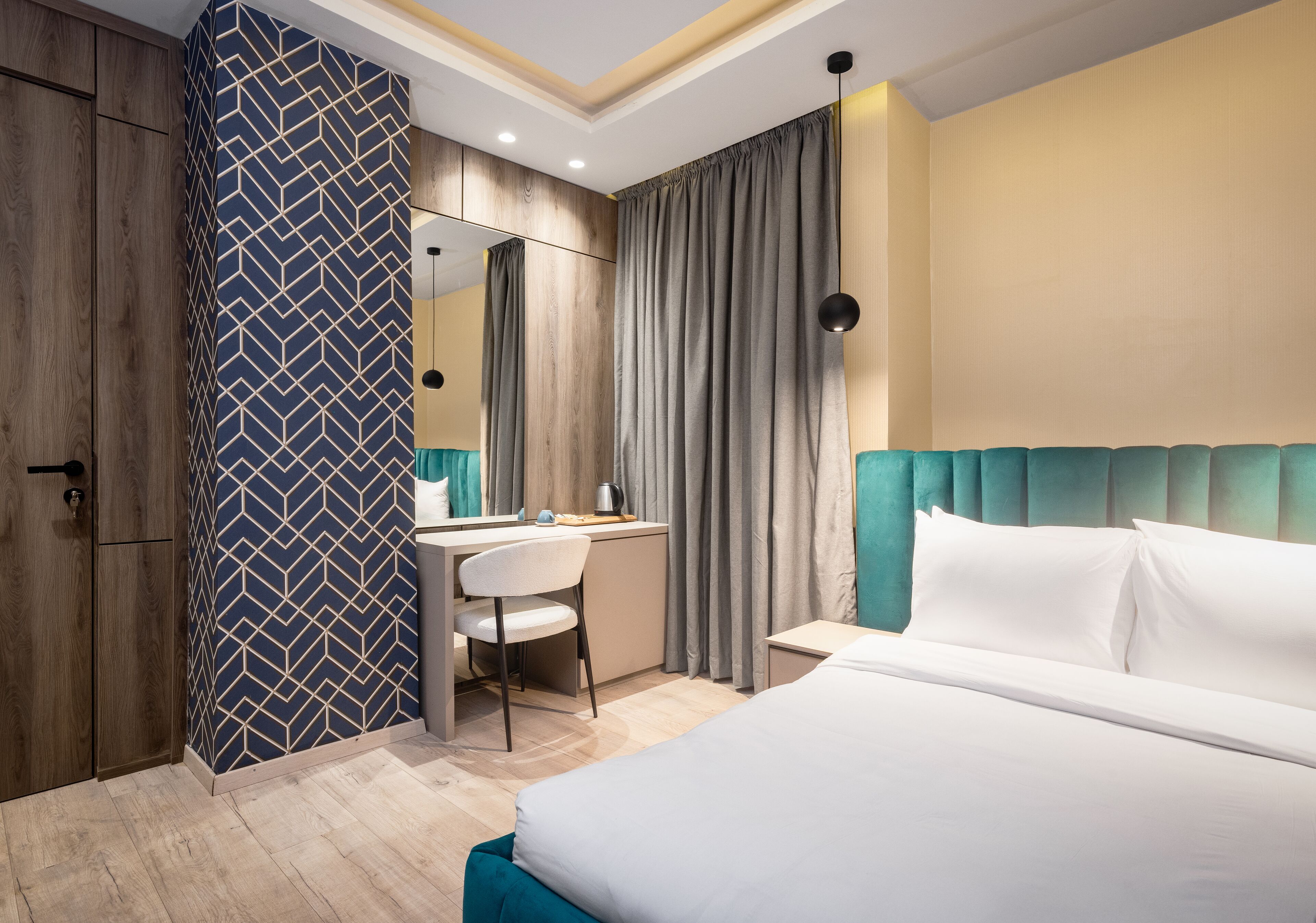 A modern hotel room with a bed, a desk, and a mirror.