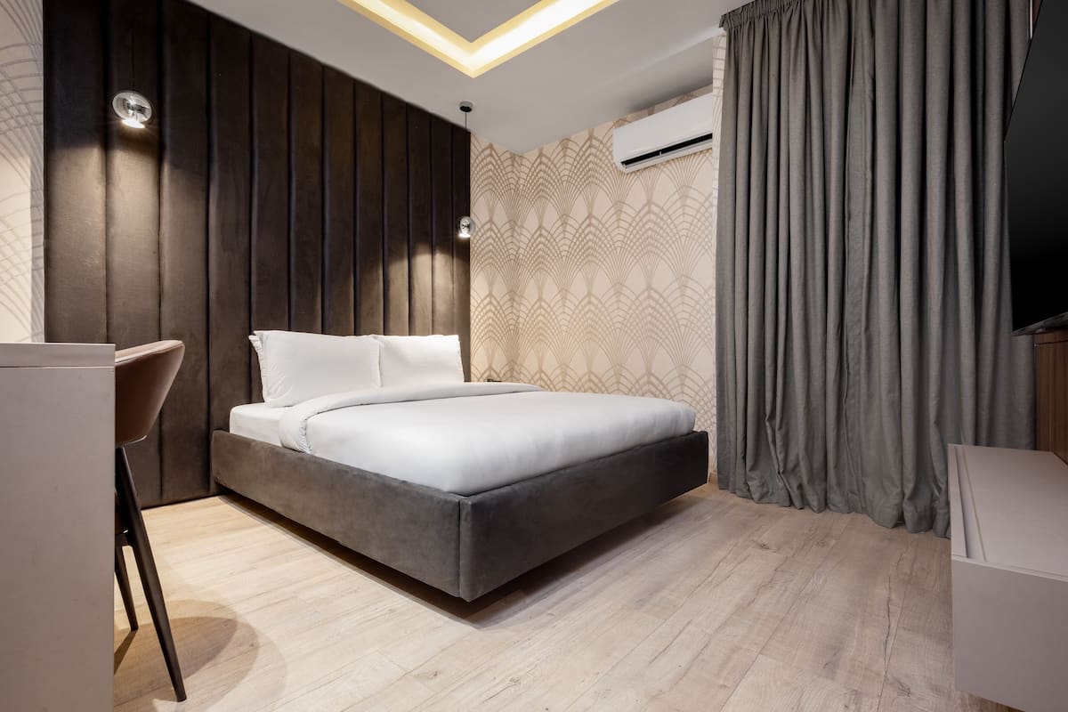 A modern bedroom with a bed, a desk, and a TV.