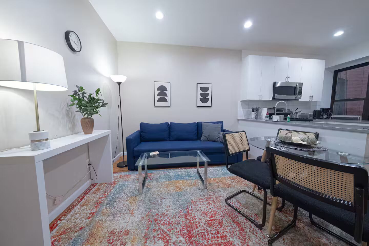 A compact living space with a sofa, a coffee table, a dining area, and a kitchenette.