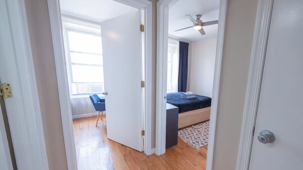 Une chambre à coucher avec un lit, un ventilateur de plafond et une fenêtre avec des rideaux.
