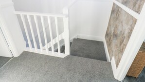 A staircase with a white railing, carpeted steps, and a corner wall with a textured panel. - 16 Salvin Terrace (Stockton-on-Tees)
