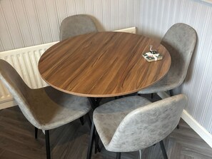Ein runder Holztisch mit vier grau gepolsterten Stühlen.