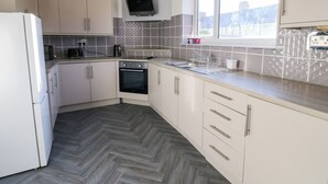 A modern kitchen with white cabinets, a built-in oven, a microwave, and a window providing natural light. - 16 Salvin Terrace (Stockton-on-Tees)