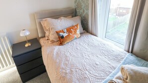 A bedroom with a bed, a nightstand, a lamp, and a window with a view of the outside. - 16 Salvin Terrace (Stockton-on-Tees)