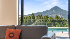 Ein Zimmer mit großem Fenster, Blick auf Berg und Schwimmbecken.