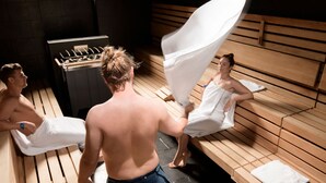A sauna with wooden benches and a visible sauna heater. - Aktiv- & Gesundheitsresort das GXUND (Bad Hofgastein)