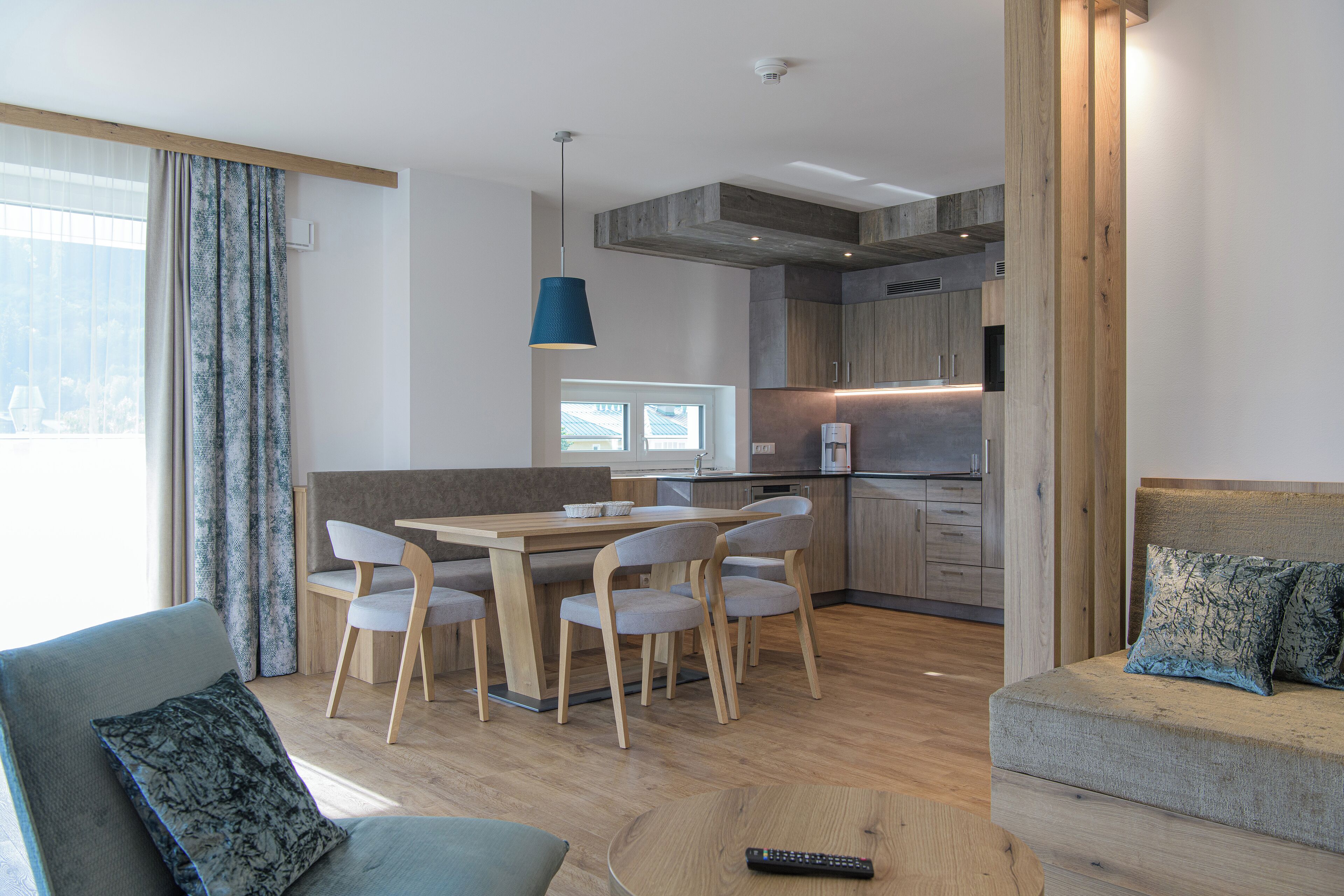 Una sala de estar moderna con comedor, cocina y un amplio ventanal con cortinas.