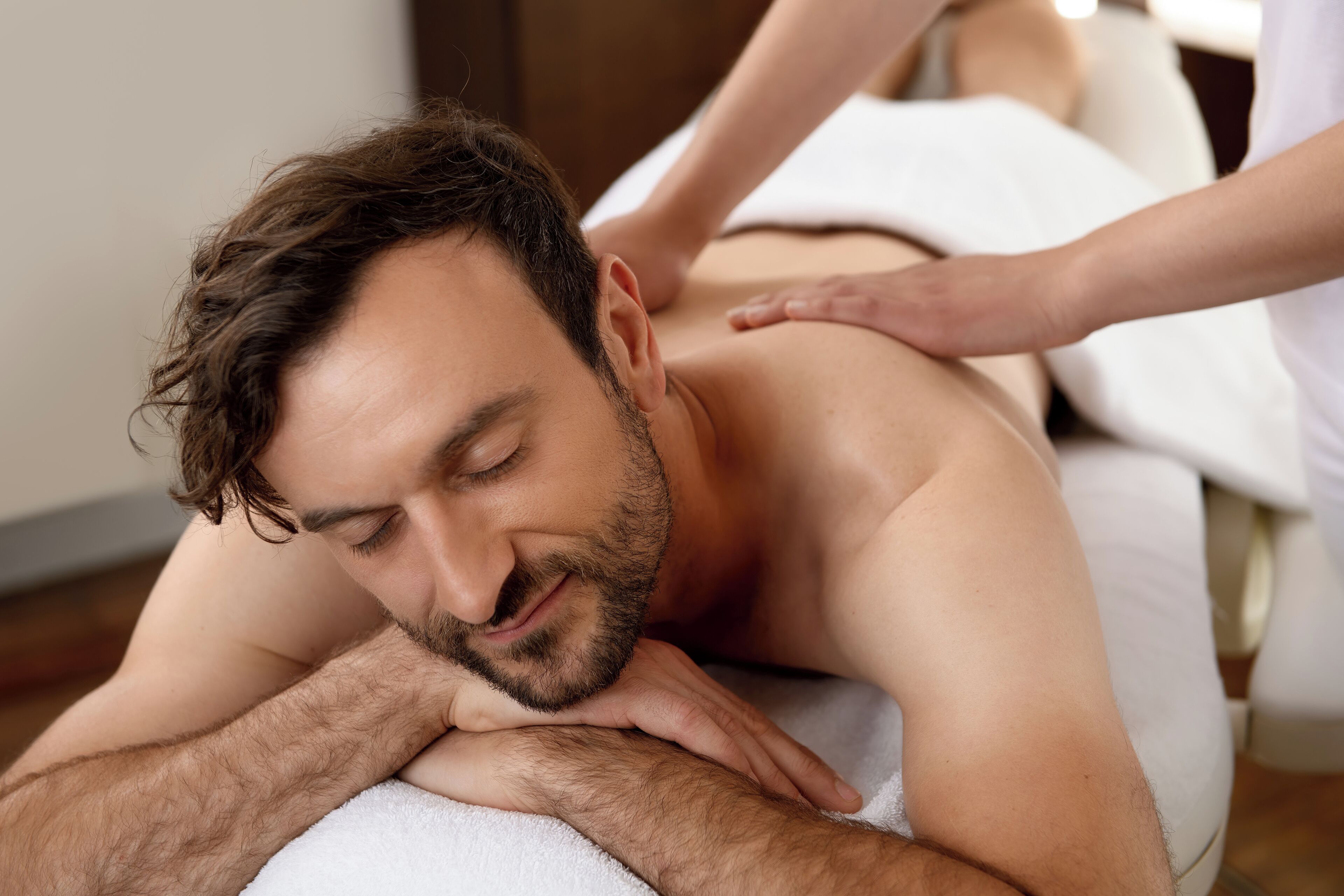 A person receiving a back massage on a massage table.