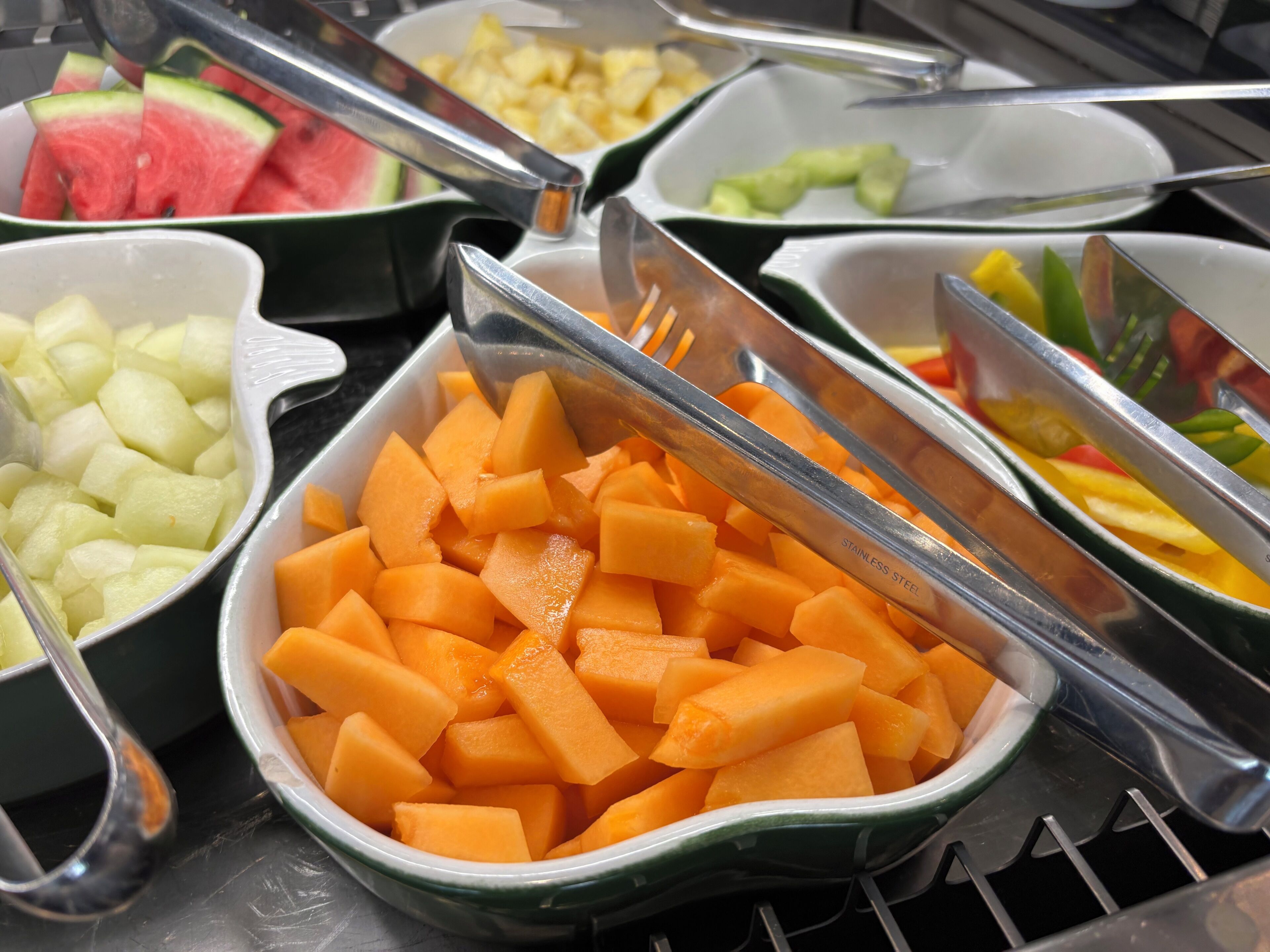 A buffet with various fruits and vegetables, including watermelon, pineapple, and carrots.