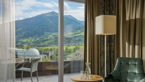 A room with a view of a mountain, a table with glasses, a chair, and a lamp. - Aktiv- & Gesundheitsresort das GXUND (Bad Hofgastein)