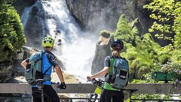 Two cyclists with bicycles near a waterfall.