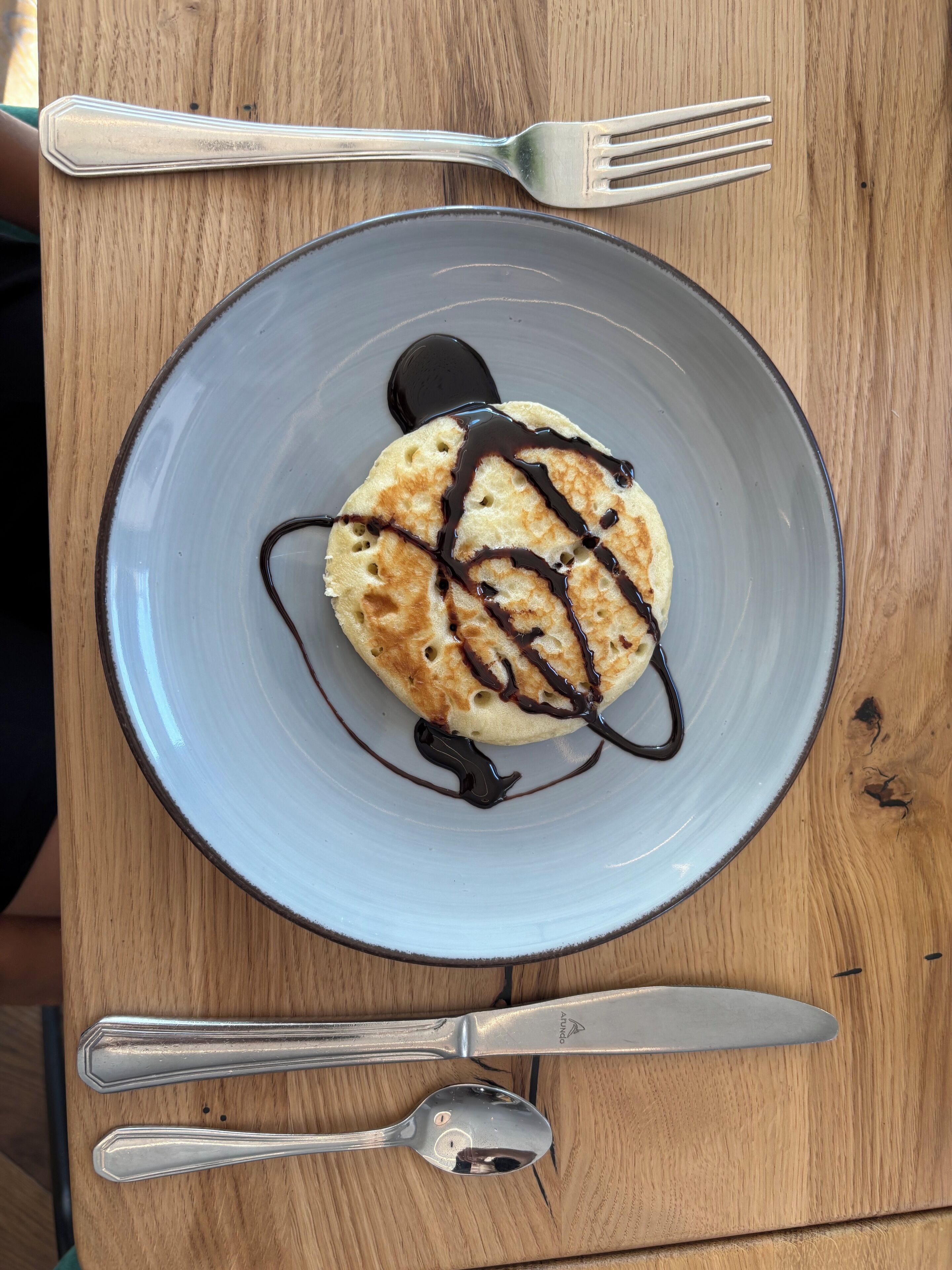 Un postre en un plato, con un tenedor y un cuchillo a un lado.
