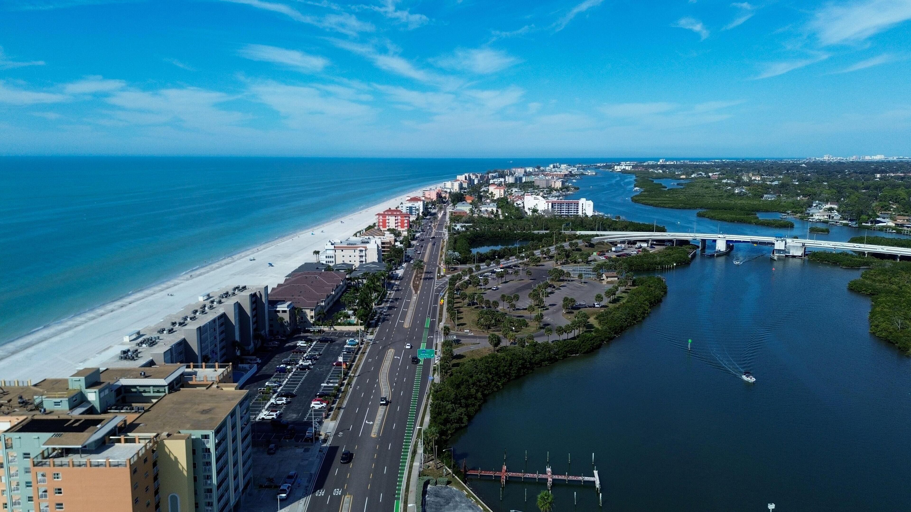 A coastal cityscape with a beach, a river, and a bridge.