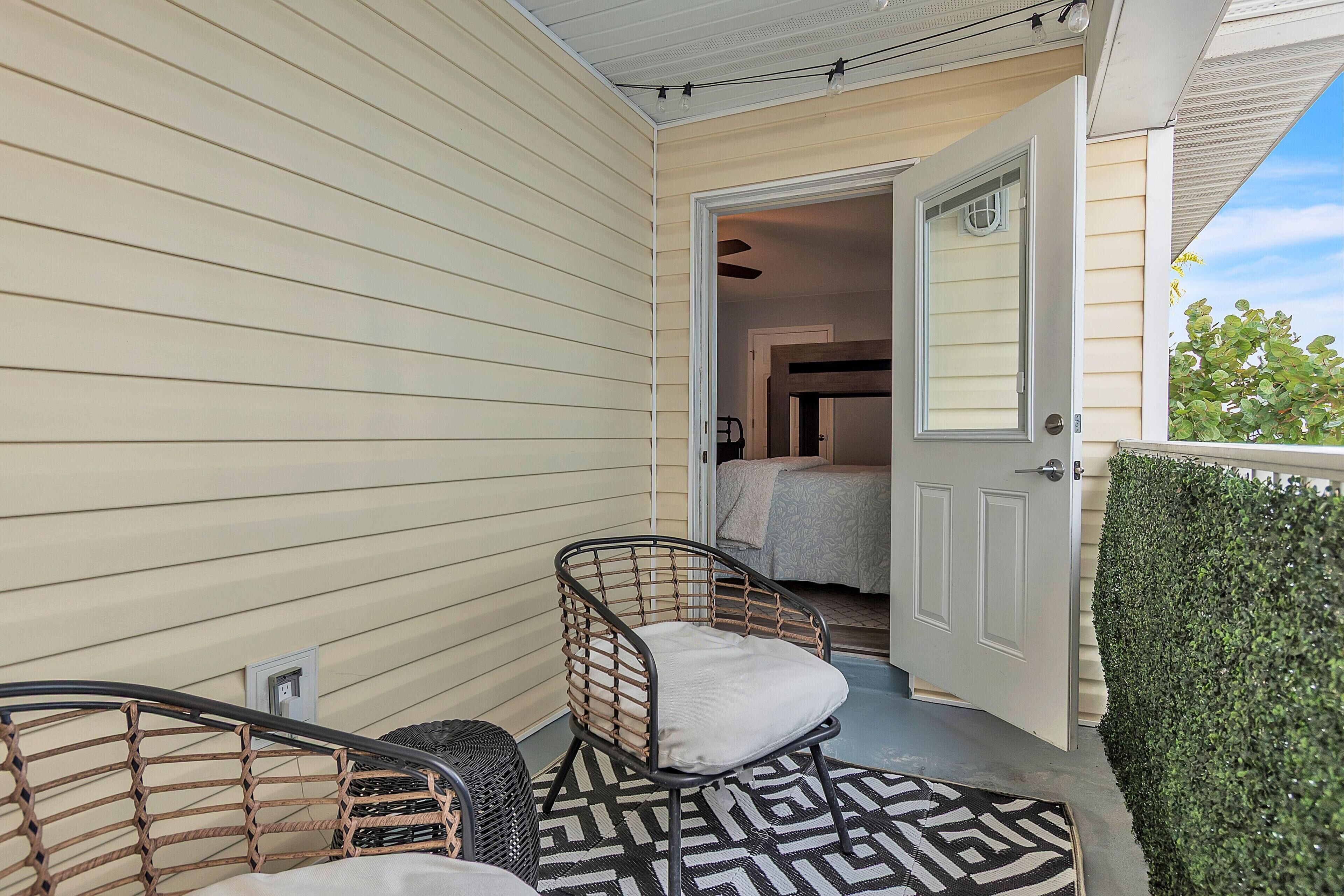 A covered porch with wicker chairs and a patterned rug.