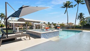 A pool area with lounge chairs, a covered seating area, and a view of the surrounding buildings.
