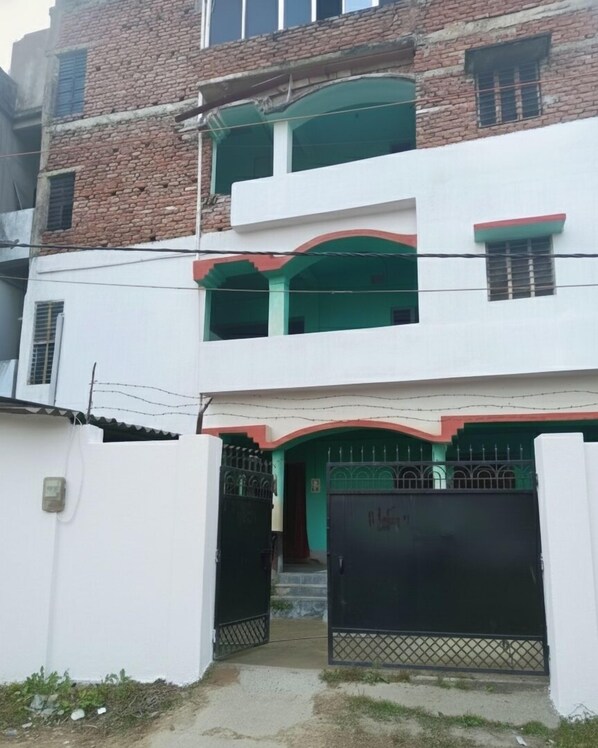 A two-story building with a gated entrance and a balcony. - santosh lodge (Muzaffarpur)