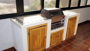 Una cocina con una parrilla empotrada, armarios de madera y salpicadero de azulejos.