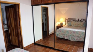 Un dormitorio con cama, mesita de noche, lámpara y armario de madera.