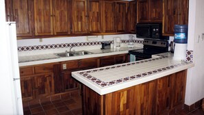 Una cocina con armarios de madera, microondas, estufa y dispensador de agua.